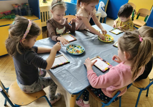 dzieci ozdabiają guzikami ramki na zdjęcia