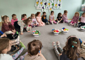 Dzieci wyjmują pranie z misek i przy pomocy klamerek wieszają pranie na sznurku.