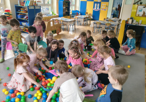 Dzieci sprzątają szufelkami kurz,którym były kolorowe kulki