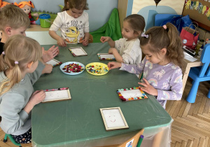 dzieci ozdabiają guzikami ramki na zdjęcia