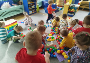 Dzieci sprzątają szufelkami kurz,którym były kolorowe kulki