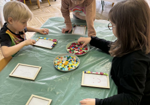 dzieci ozdabiają guzikami ramki na zdjęcia