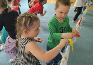 Dzieci wieszają pranie na sznurku, używając klamerek