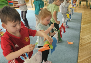 Dzieci wieszają pranie na sznurku, używając klamerek