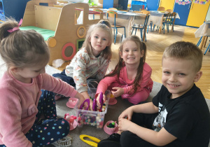 Dzieci w małych grupach nakładają szczypcami kulki w kolorach odpowiadających kolorze podstawy filiżanki.