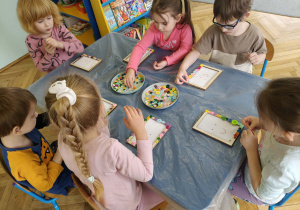 dzieci ozdabiają guzikami ramki na zdjęcia