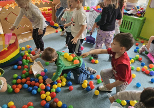 Dzieci sprzątają szufelkami kurz,którym były kolorowe kulki