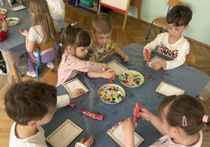 dzieci ozdabiają guzikami ramki na zdjęcia