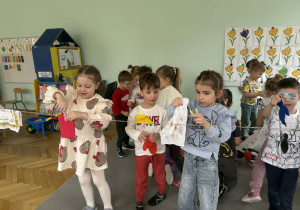 Dzieci wieszają pranie na sznurku, używając klamerek