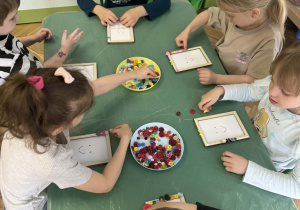 dzieci ozdabiają guzikami ramki na zdjęcia