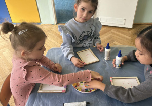 dzieci ozdabiają guzikami ramki na zdjęcia