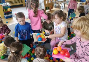 Dzieci sprzątają szufelkami kurz,którym były kolorowe kulki