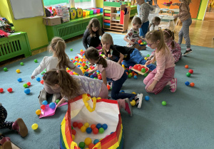 Dzieci sprzątają szufelkami kurz,którym były kolorowe kulki