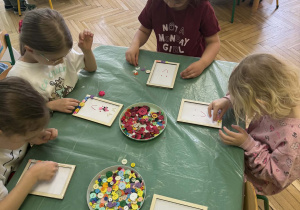 dzieci ozdabiają guzikami ramki na zdjęcia