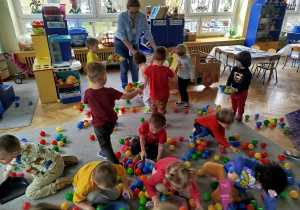 Dzieci sprzątają szufelkami kurz,którym były kolorowe kulki