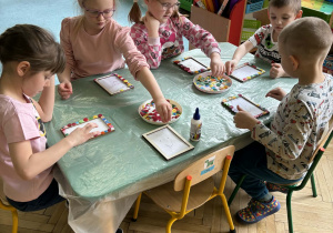 dzieci ozdabiają guzikami ramki na zdjęcia