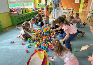 Dzieci sprzątają szufelkami kurz,którym były kolorowe kulki