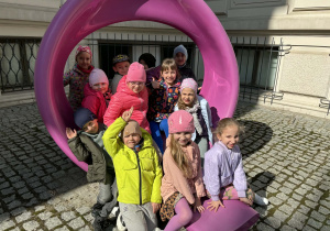 dzieci pozują do zdjęcia siedząc na ławkach na terenie Muzeum Sztuki