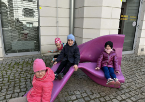 dzieci pozują do zdjęcia siedząc na ławkach na terenie Muzeum Sztuki