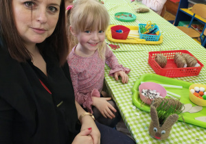 Rodzice wraz z dziećmi przy stołach wykonują wielkanocnego króliczka.