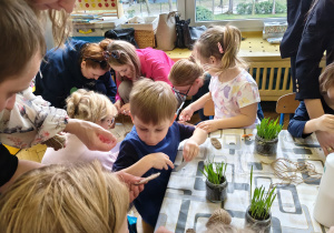 Rodzice wraz z dziećmi przy stołach wykonują wielkanocnego króliczka.