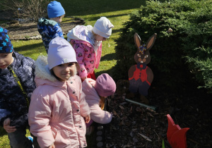 Dzieci szukają w ogrodzie ukrytych jajek