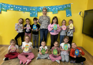 dzieci pozują do zdjęcia z wykonanymi pisankami