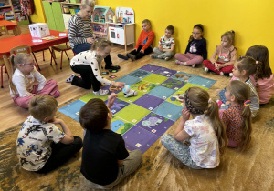 dzieci programują robota Franka i wykonują na macie do kodowania zadania,