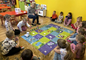 dzieci programują robota Franka i wykonują na macie do kodowania zadania,