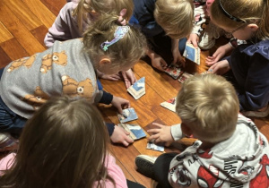 dzieci siedzą w grupach i układają puzzle