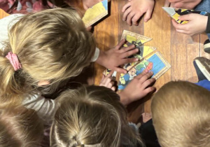 dzieci siedzą w grupach i układają puzzle