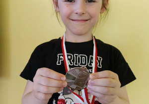 dziewczynka prezentuje medal, który zdobyła na zawodach tanecznych