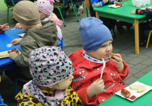 dzieci siedzą przy stolikach na tarasie spożywając posiłek