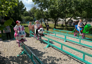 dzieci ścigają się na ruchomych plastikowych zwierzętach