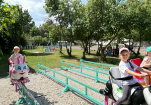 dzieci ścigają się na ruchomych plastikowych zwierzętach