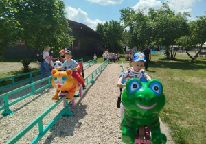 dzieci ścigają się na ruchomych plastikowych zwierzętach