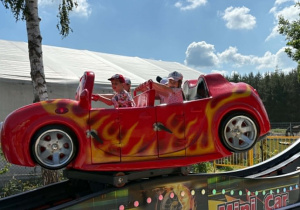 dzieci siedzą w ruchomym aucie i kręcą się w koło