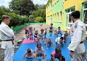 dzieci uczestniczą w pokazowych zajęciach judo