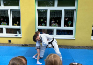 dzieci uczestniczą w pokazowych zajęciach judo