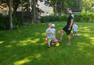 Dzieci wykonują slalom z piłką.