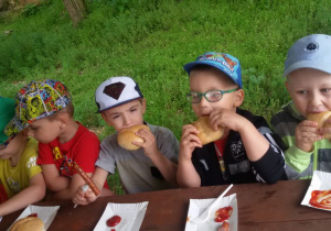 Dzieci jedzą kiełbaski z ogniska