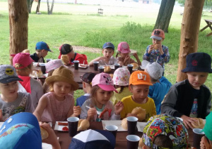 Dzieci jedzą kiełbaski z ogniska
