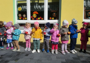 Grupa dzieci pozuje trzymając jabłka w dłoniach