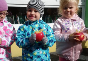 Dwójka dzieci pozuje trzymając jabłka w dłoniach