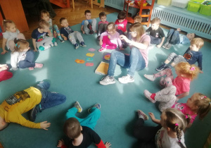 Dzieci wraz z Panią Martą ćwiczą na dywanie.