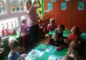 Pani Marta prezentuje dzieciom jak wykonać dziób bociana.