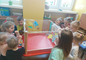 Grupa dzieci jednocześnie maluje na przezroczystej powierzchni
