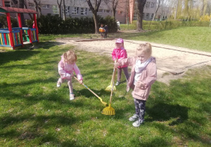 Dzieci garbią trawnik w ogrodzie przedszkolny.