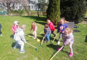 Dzieci garbią trawnik w ogrodzie przedszkolny.