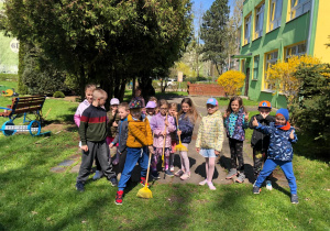 Dzieci stoją w ogrodzie przedszkolnym i pozują do zdjęcia